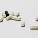 Integratori per il seno: bottiglie e capsule su sfondo bianco, simbolo di discussione su efficacia e miti.